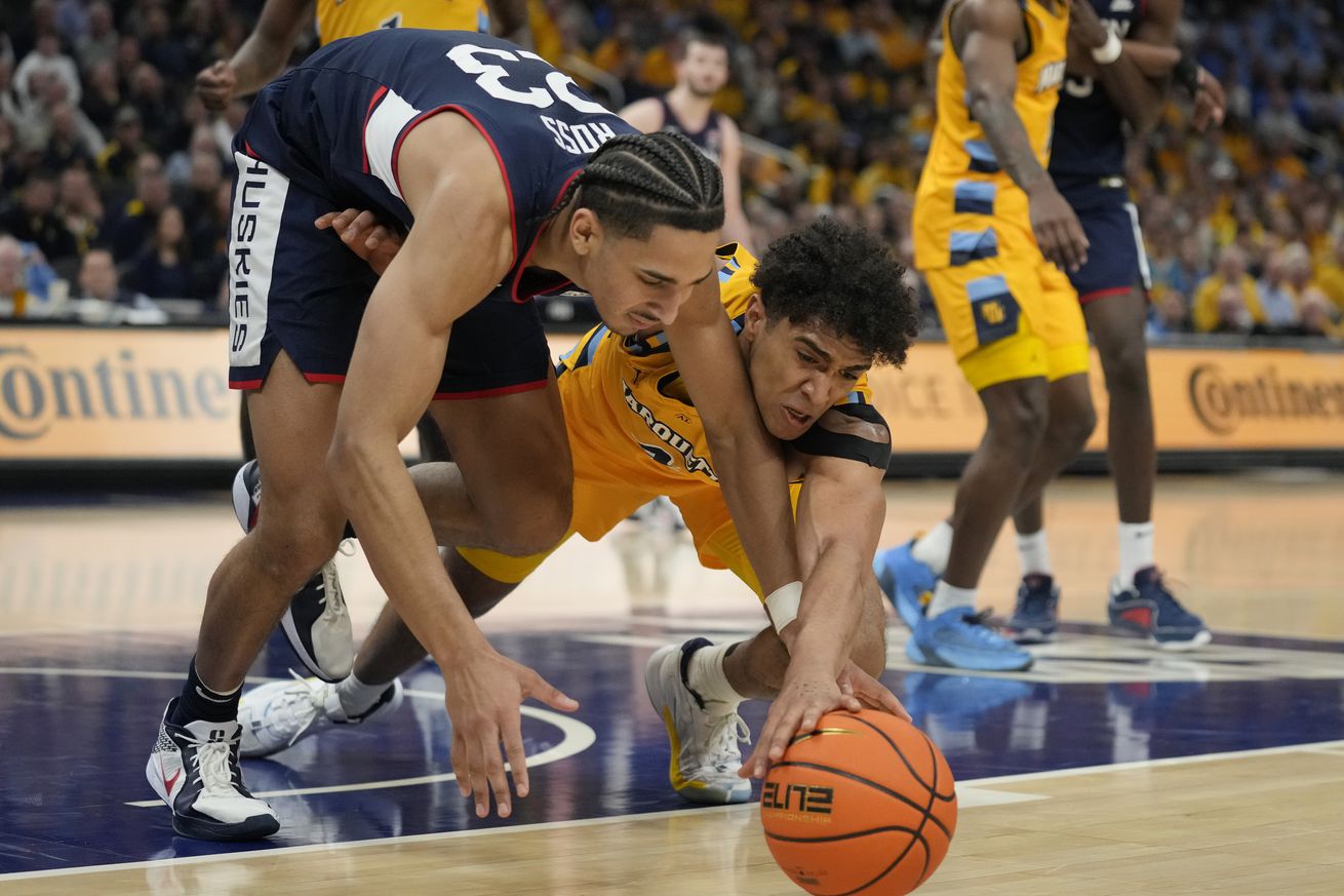 Jayden Ross #23 of the Connecticut Huskies and Stevie Mitchell #4 of the Marquette Golden Eagles dive for the ball during the second half at Fiserv Forum on February 01, 2025 in Milwaukee, Wisconsin.