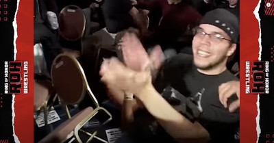 Screengrab from YouTube showing a fan sitting ringside at the ROH 6th Anniversary show, clapping and smiling after Nigel McGuinness was thrown over the barricade right next to him.